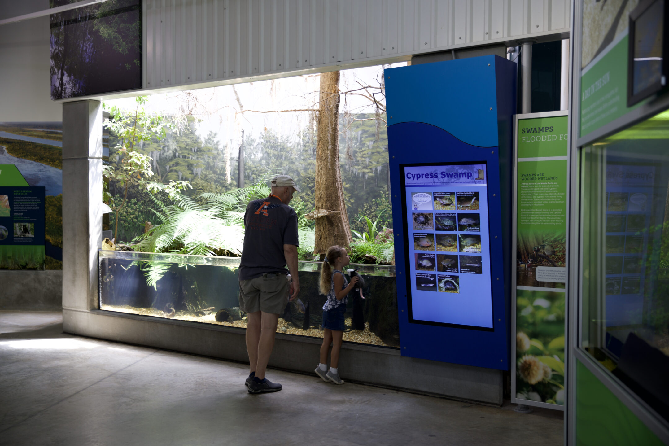 a father and daughter looking at one of the exhibits inside the aquarium